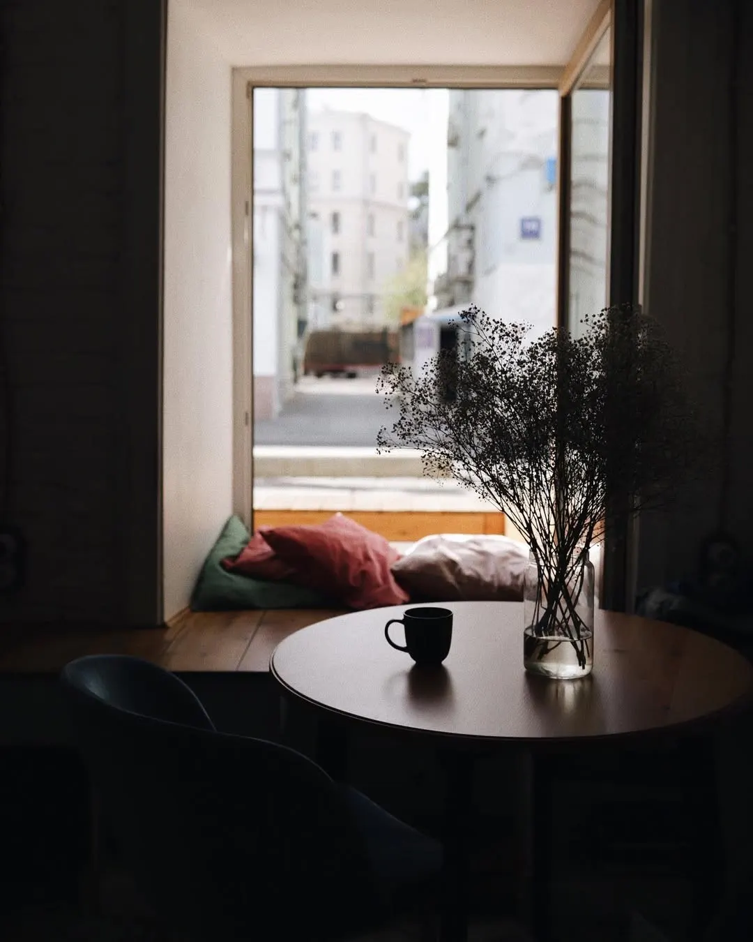 A windowsill table with a cup of coffee and pillows